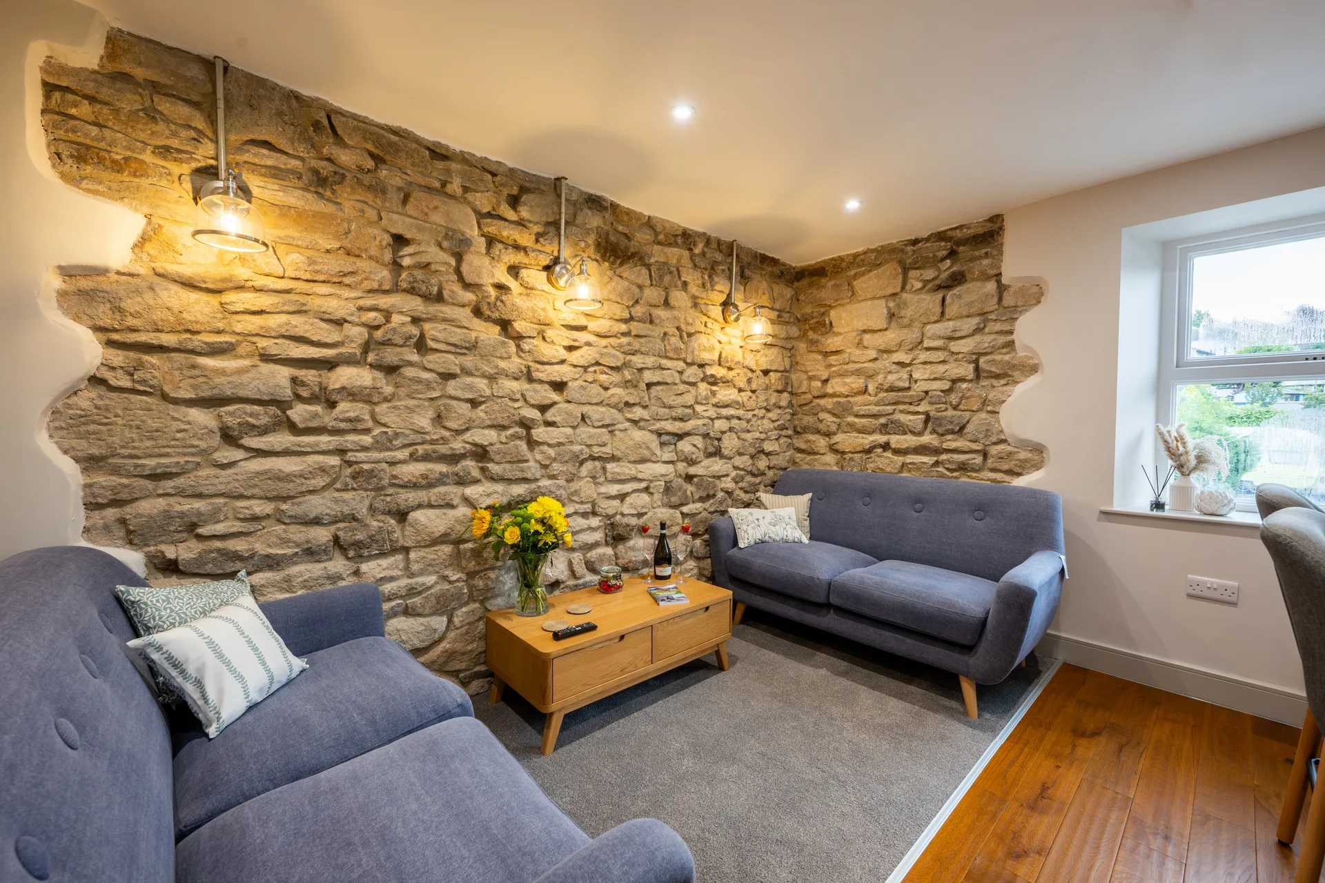 Stone-walled living room with blue sofas and a window